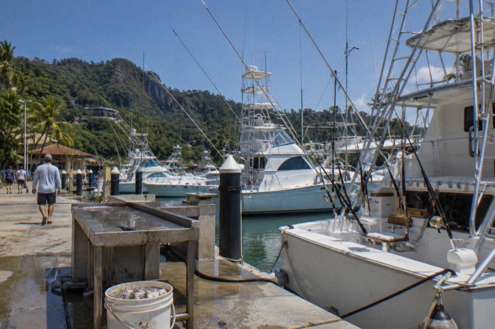Fishing boats and masts at a marina in Quepos under a bright sky
