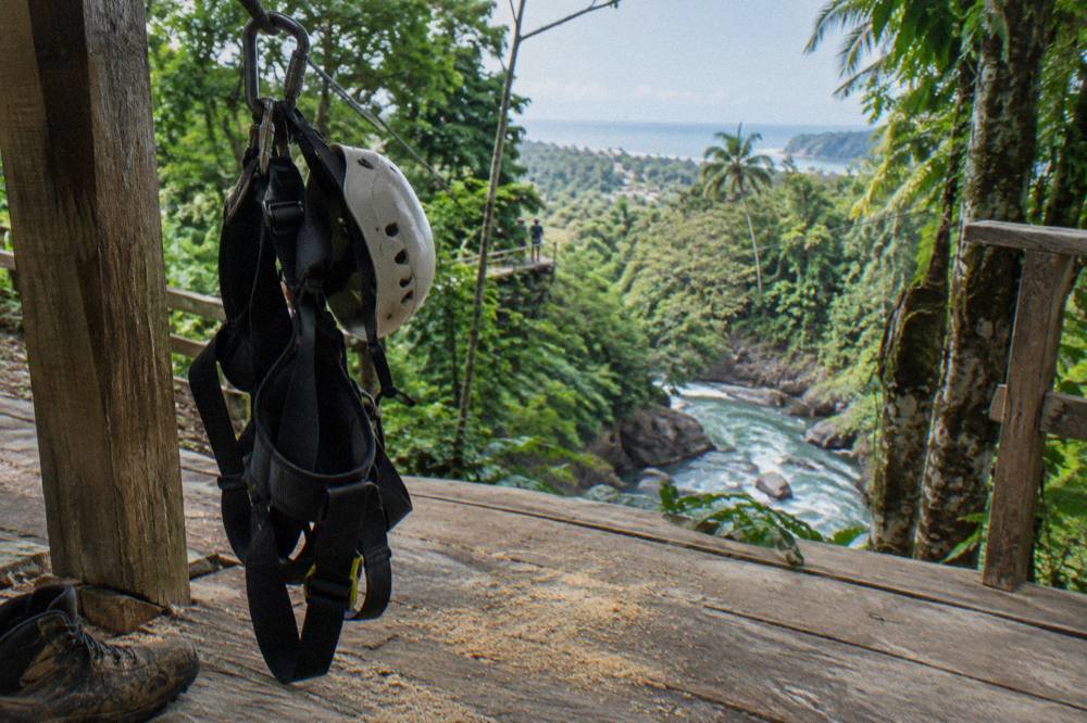 Zipline harness and helmet hanging on a hook at a wooden platform in the rainforest