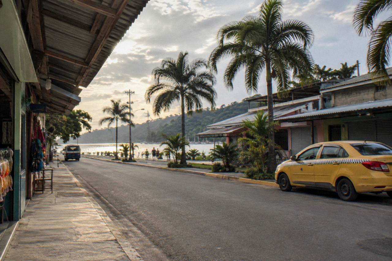 Quiet street in Quepos town with palm trees and small shop fronts in late afternoon light