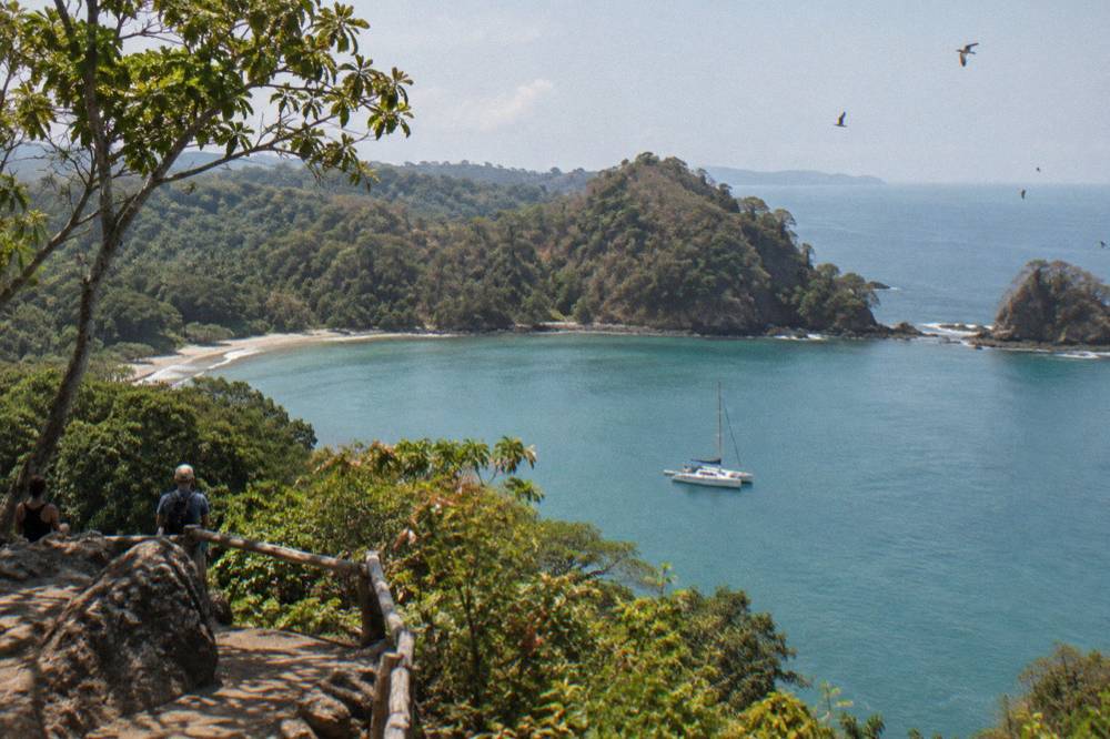 Catamaran anchored in a calm bay with forested hills behind