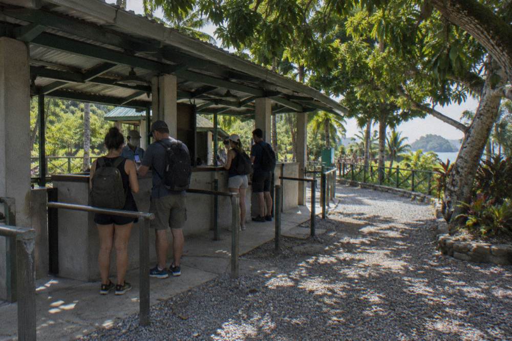 A park entrance gate with visitors showing tickets to staff in morning light