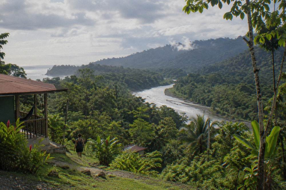 River valley with forested slopes under mixed clouds in green season