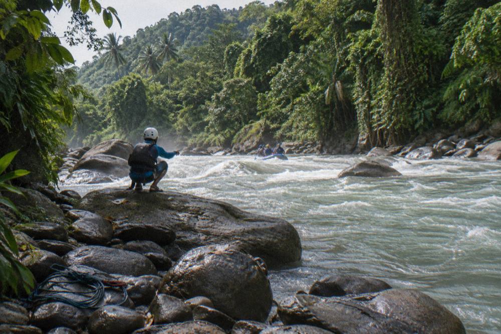Guide pointing out river line to paddlers before a rapid