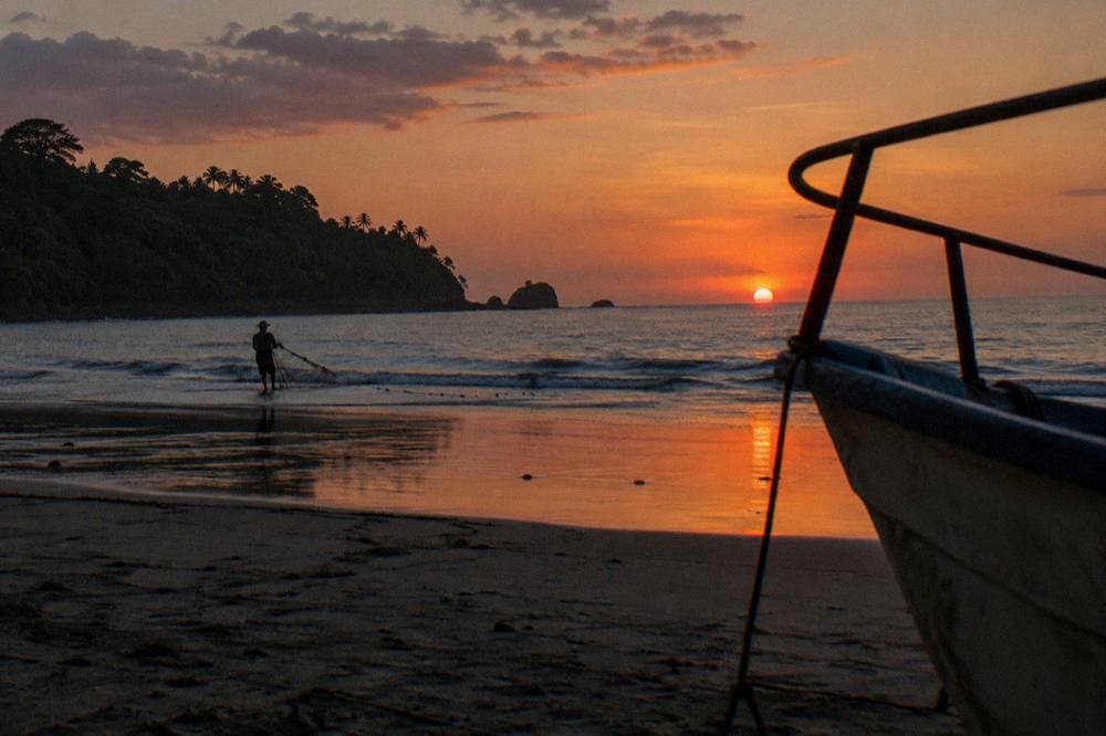 Sun sinking into the Pacific Ocean behind a silhouetted boat rail