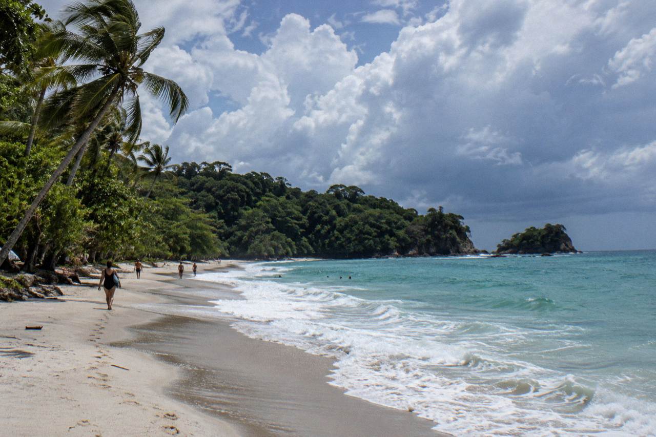 Palm fringed beach under a partly cloudy sky on the Central Pacific coast at midday