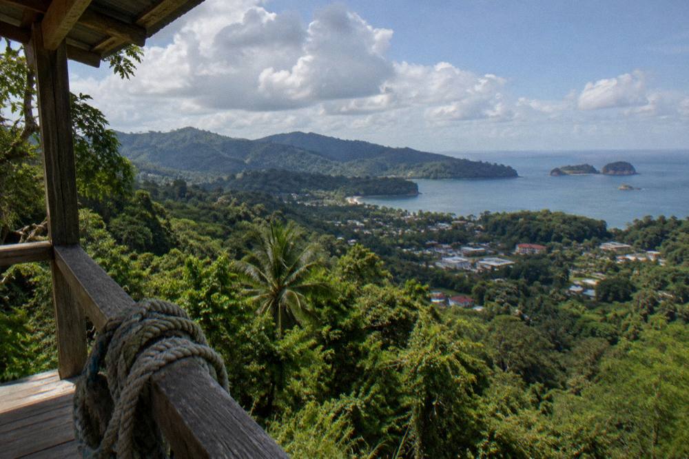 Rainforest valley seen from a high wooden canopy platform under a partly cloudy sky