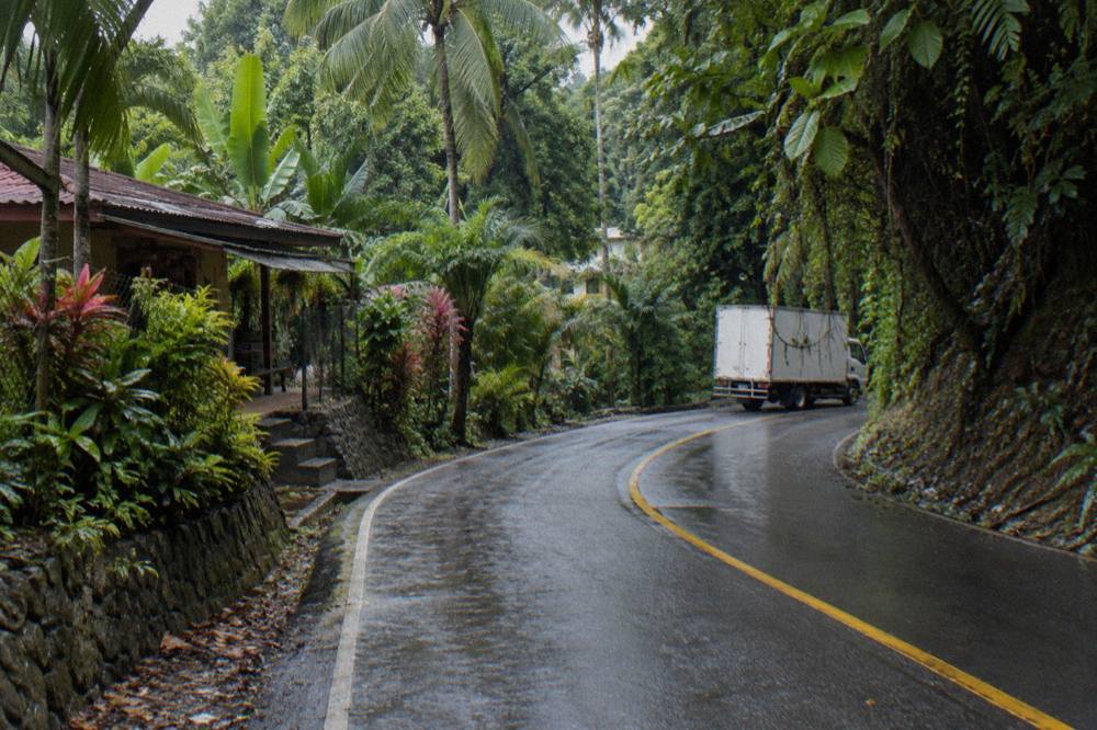 Winding two-lane road through dense rainforest hills on the way to Manuel Antonio