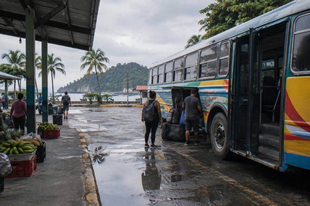 Colorful public bus parked at a small town terminal under overcast sky