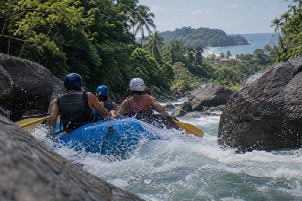 Inflatable raft running a foamy rapid between boulders in a green river canyon